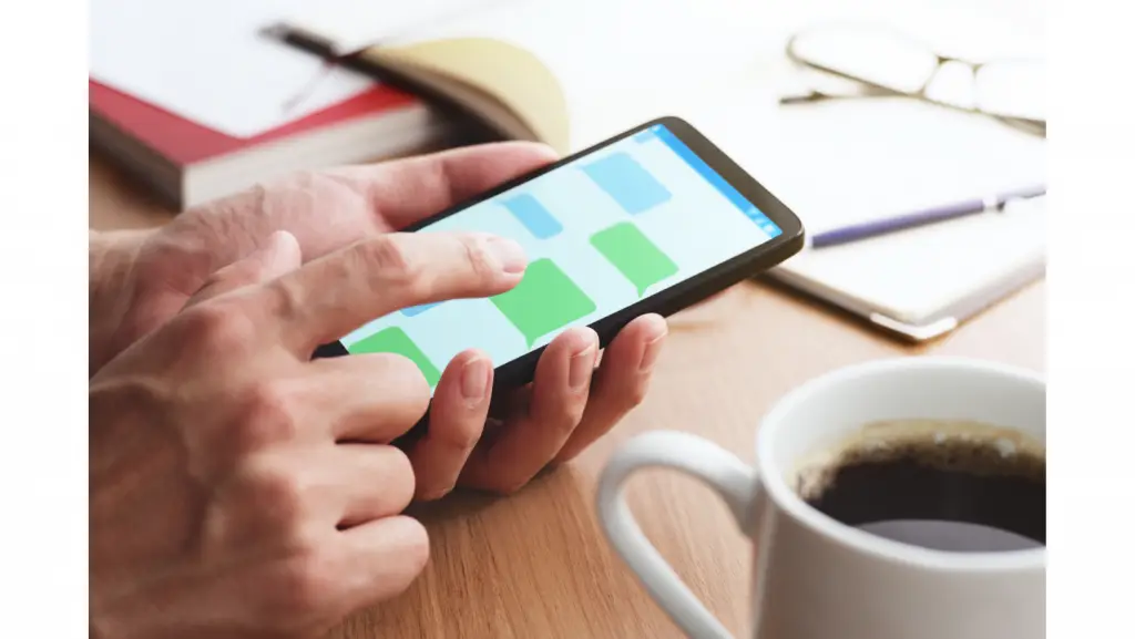 manos sosteniendo smart phone ejemplos de saludos para clientes por WhatsApp